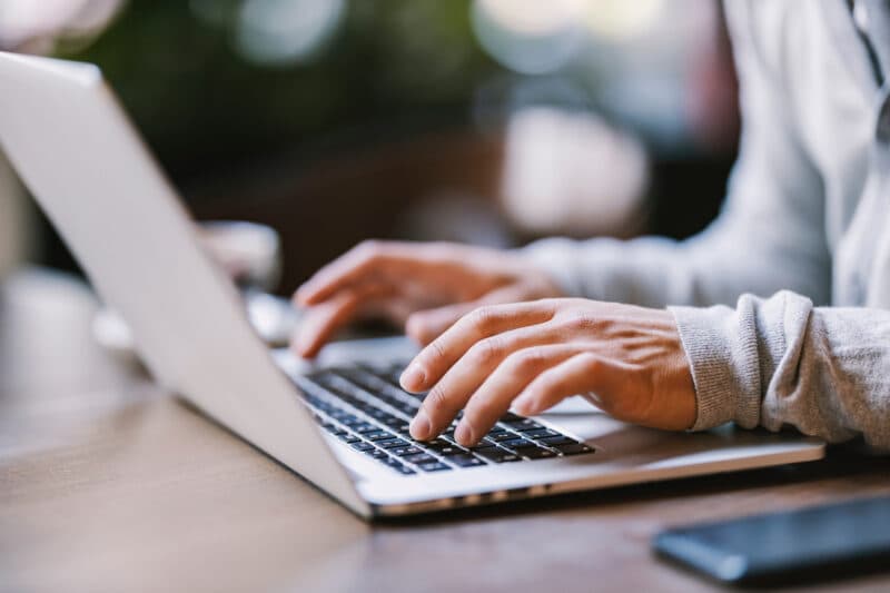 Cropped view of hands actively typing on a laptop keyboard, highlighting the movement and engagement with the device.
